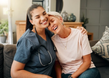 A female caregiver and an elderly woman hugging each other