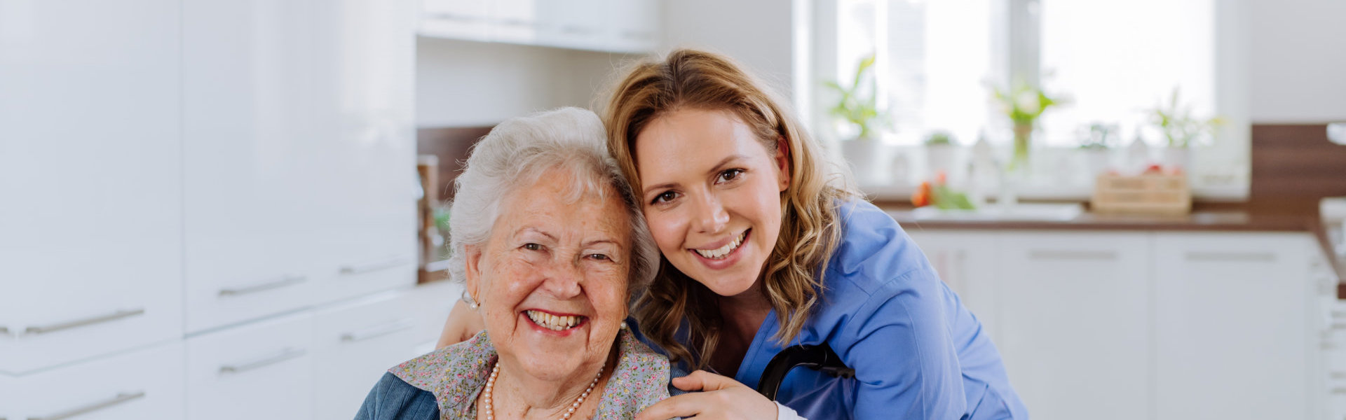 An elderly woman and a female caregiver smiling together