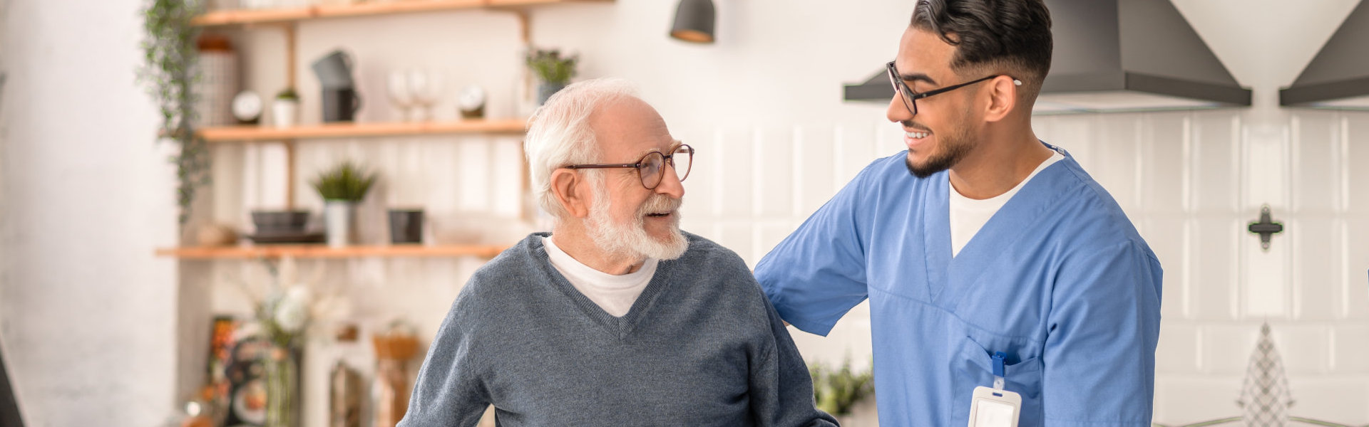 A male caregiver assisting an elderly man to stand