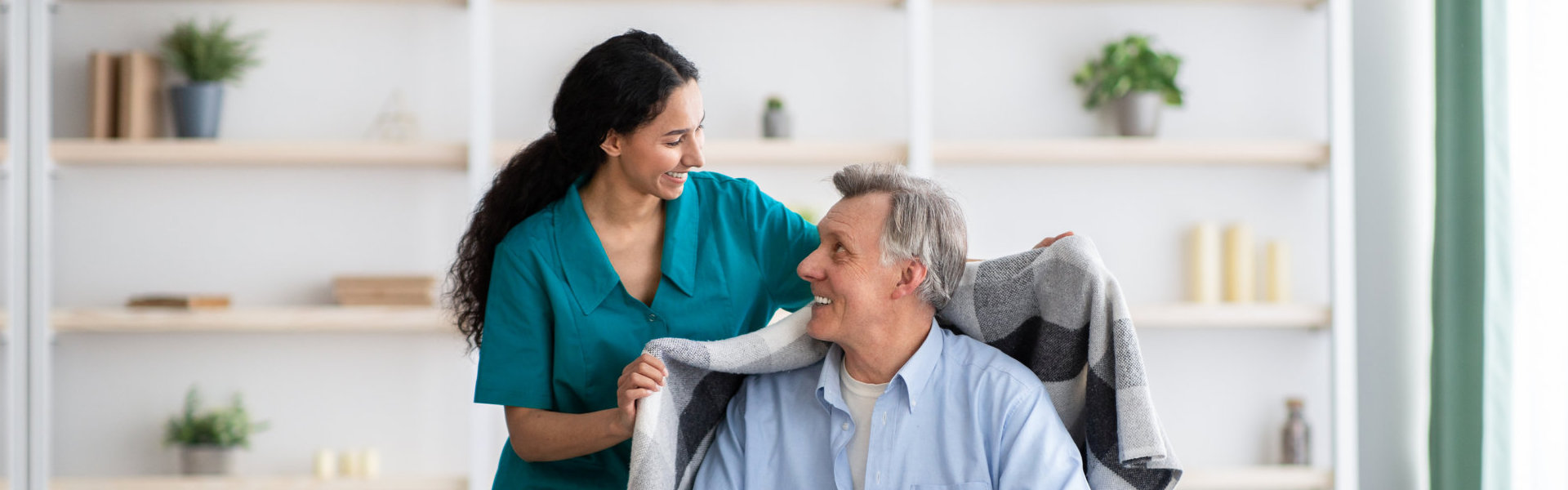 A female caregiver putting a coat to an elderly man